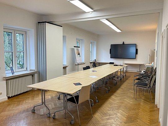Ein Konferenzraum mit Tisch und Bildschirm